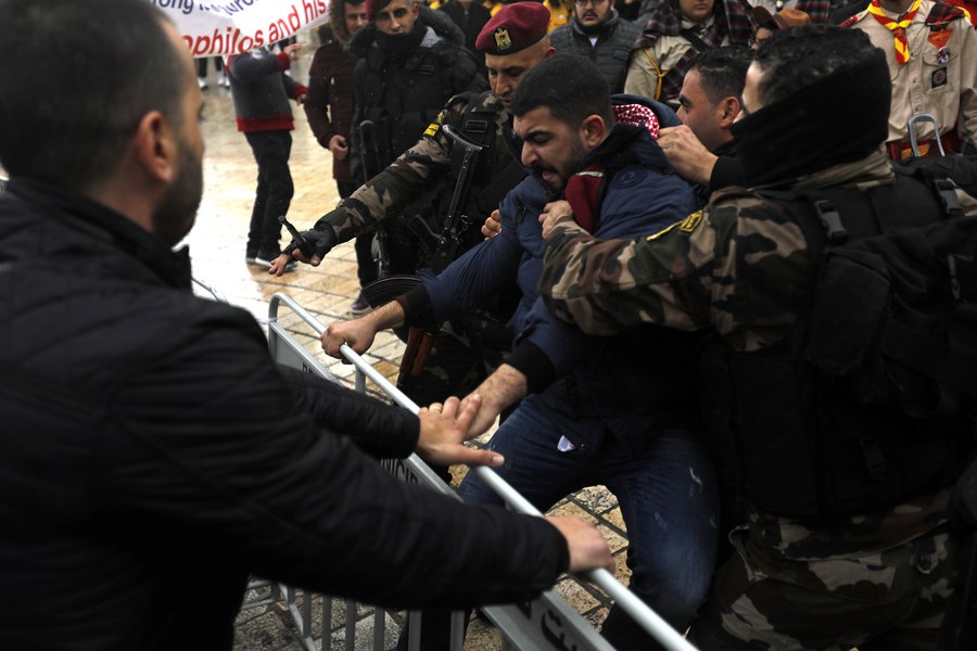 epa06419978 Palestinian security forces push away demonstrators from the convoy of Greek Orthodox Patriarch of Jerusalem Theophilos III, during a protest against his visit in the West Bank city of Bethlehem, 06 January 2018. The protest are against the Church's alleged sale of church lands to Israelis. EPA/ABED AL HASHLAMOUN