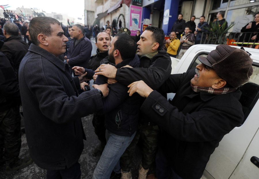 epa06419974 Palestinian security forces push away demonstrators from the convoy of Greek Orthodox Patriarch of Jerusalem Theophilos III, during a protest against his visit in the West Bank city of Bethlehem, 06 January 2018. The protest are against the Church's alleged sale of church lands to Israelis. EPA/ABED AL HASHLAMOUN